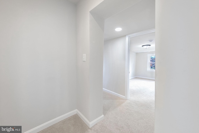 hall featuring baseboards and light carpet