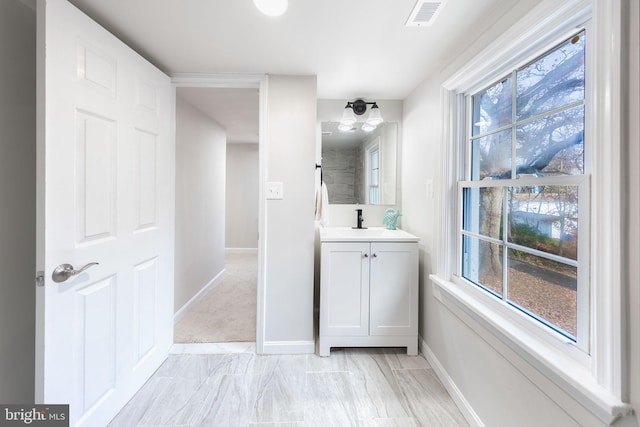 bathroom featuring a wealth of natural light, visible vents, vanity, and baseboards