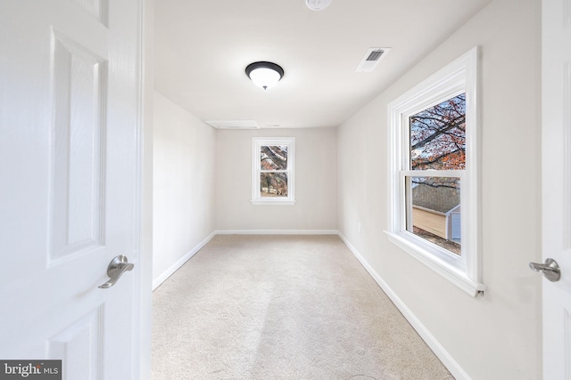 unfurnished room with baseboards, visible vents, and light carpet