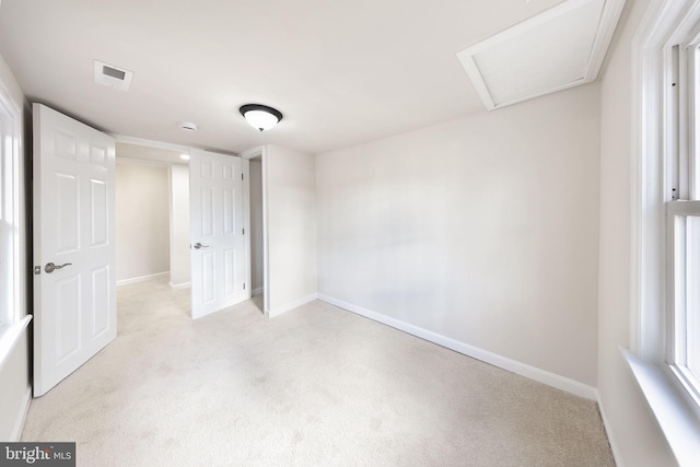 unfurnished bedroom featuring baseboards, visible vents, light colored carpet, and attic access