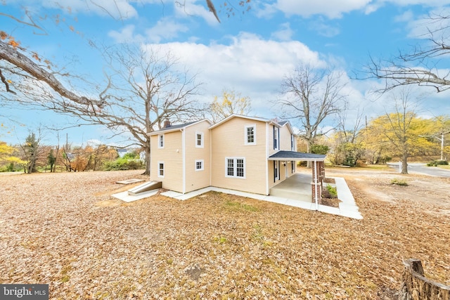 rear view of house featuring driveway and a patio