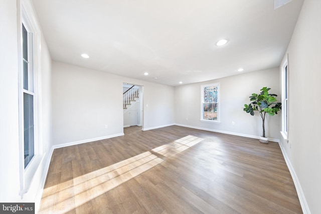 spare room featuring baseboards, recessed lighting, stairs, and wood finished floors