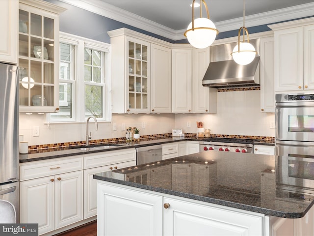 kitchen featuring a center island, a sink, stainless steel appliances, backsplash, and wall chimney exhaust hood