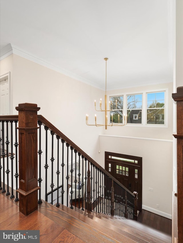 stairs with baseboards, crown molding, a chandelier, and wood finished floors