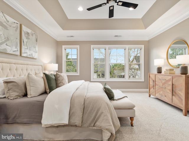 carpeted bedroom featuring a tray ceiling, visible vents, crown molding, and baseboards