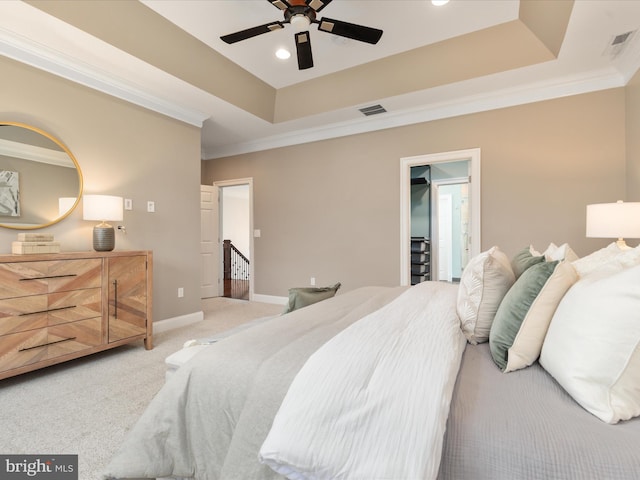 bedroom with visible vents, ornamental molding, a tray ceiling, and light colored carpet
