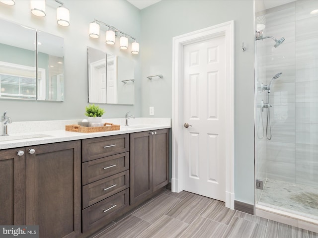bathroom featuring double vanity, a stall shower, and a sink