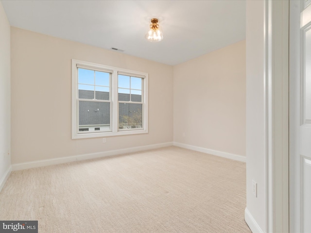 carpeted spare room featuring visible vents and baseboards