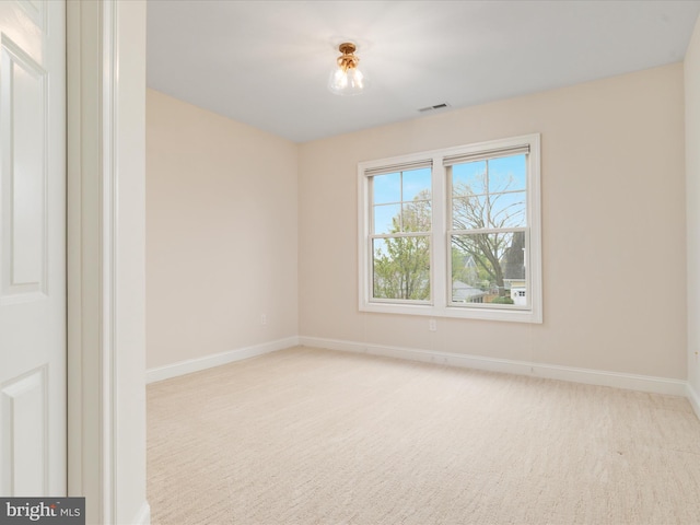 spare room featuring visible vents, baseboards, and light carpet