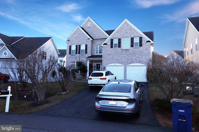 traditional home with a garage, aphalt driveway, and brick siding