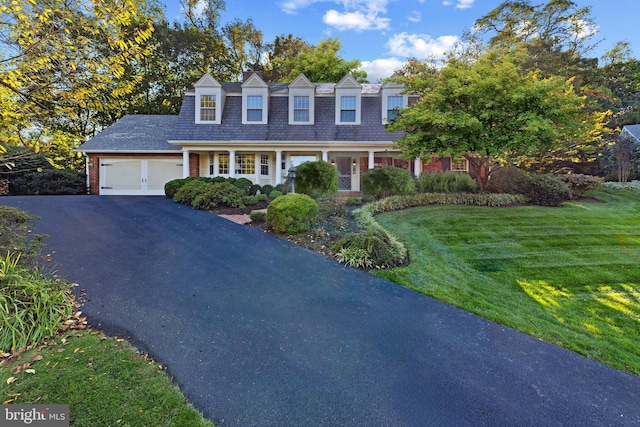 view of front of property with aphalt driveway, brick siding, an attached garage, and a front lawn