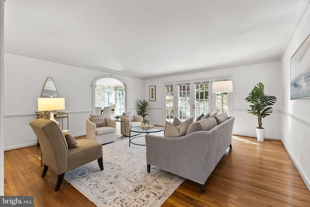 living area featuring baseboards, french doors, wood finished floors, and crown molding