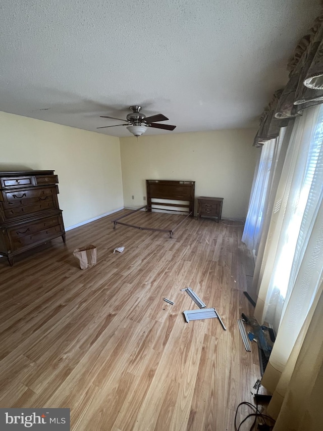 unfurnished living room featuring light wood-style floors, ceiling fan, and a textured ceiling