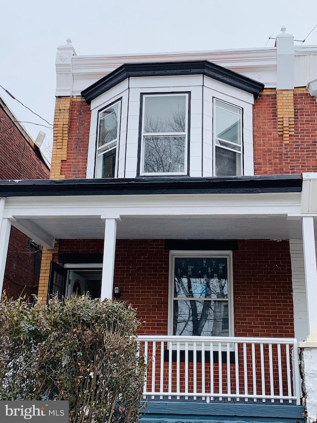 view of side of home with covered porch and brick siding