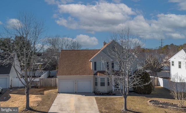 traditional-style home featuring a garage, fence, driveway, roof with shingles, and a chimney