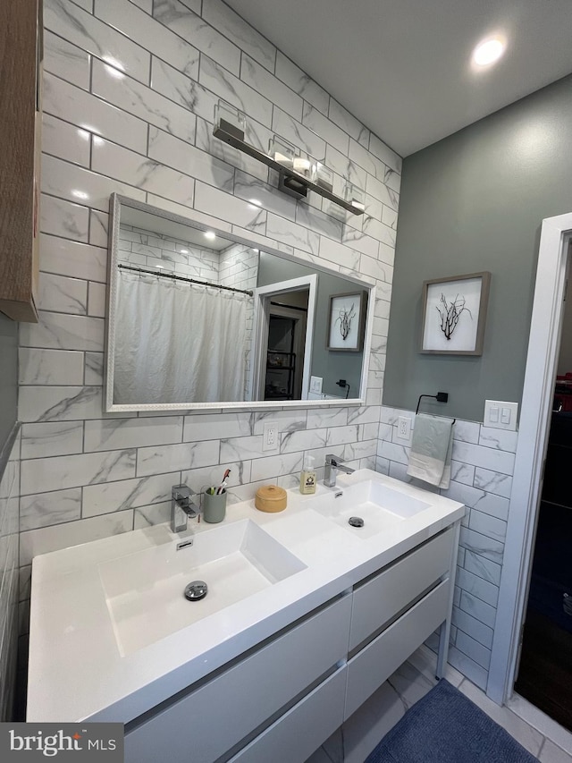 full bathroom with double vanity, tile walls, and a sink