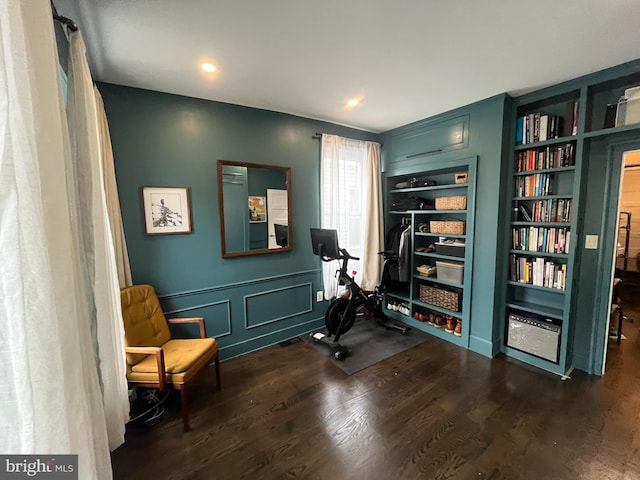 sitting room featuring built in features, dark wood finished floors, and a decorative wall