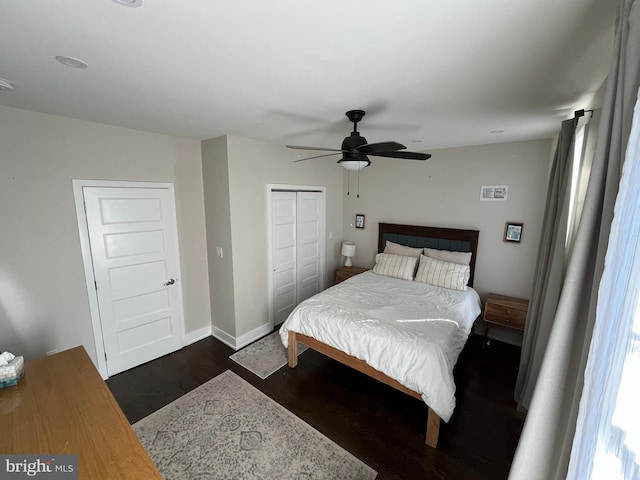 bedroom with dark wood-type flooring, a ceiling fan, visible vents, baseboards, and a closet