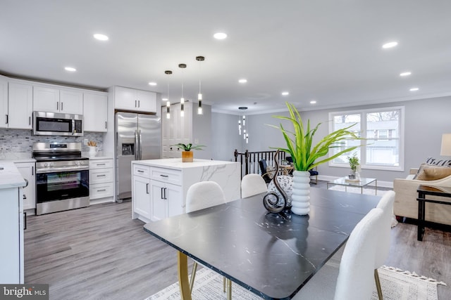 dining room with light wood-style floors, recessed lighting, crown molding, and baseboards