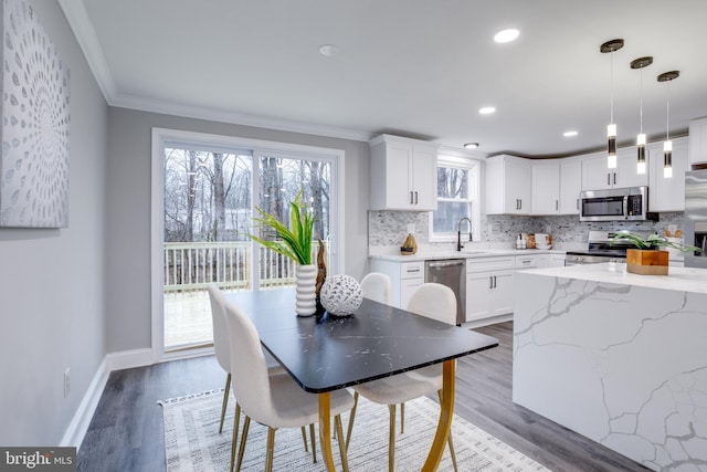 dining area featuring baseboards, ornamental molding, wood finished floors, and recessed lighting