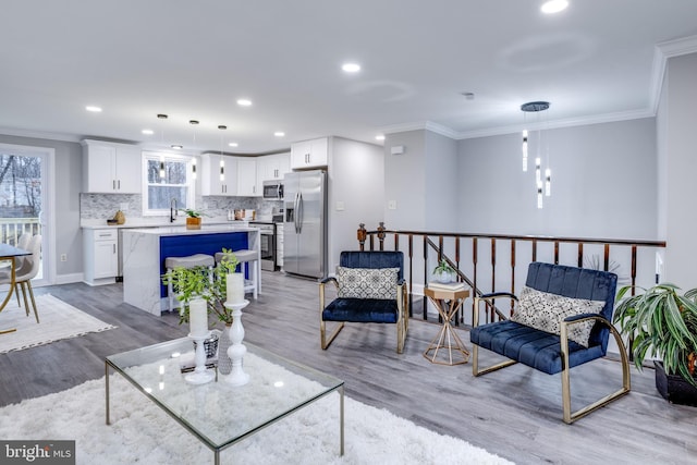 living area featuring ornamental molding, recessed lighting, and light wood finished floors