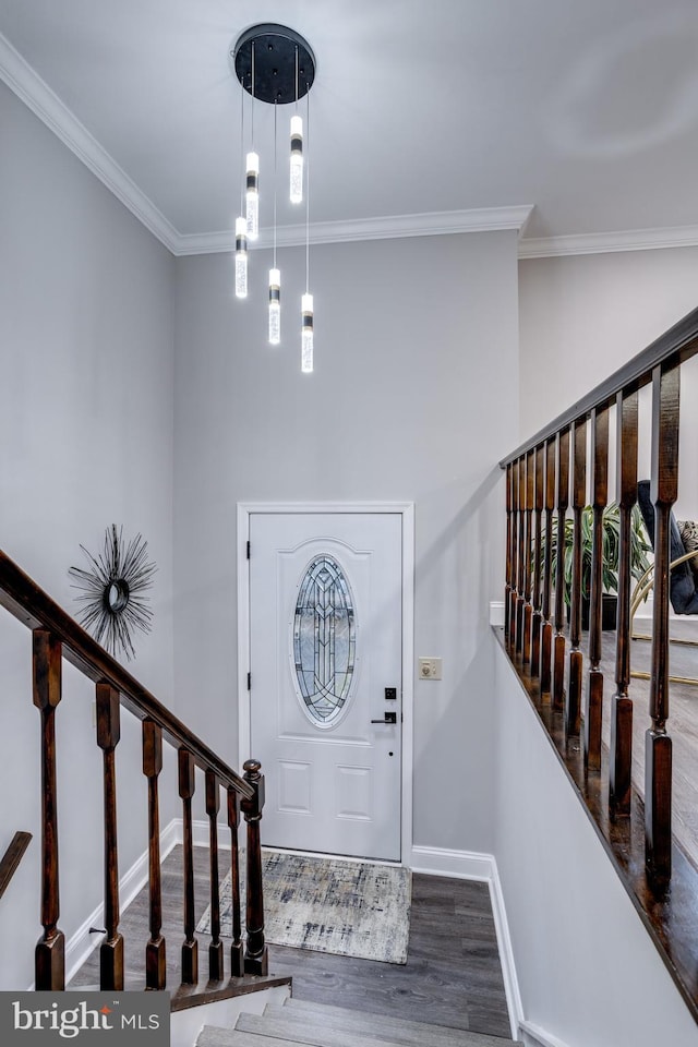 foyer entrance with ornamental molding, stairs, baseboards, and wood finished floors