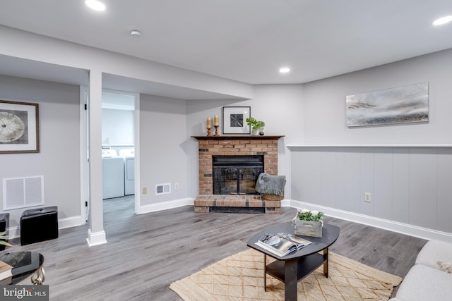 living room featuring wood finished floors, visible vents, and washer and dryer