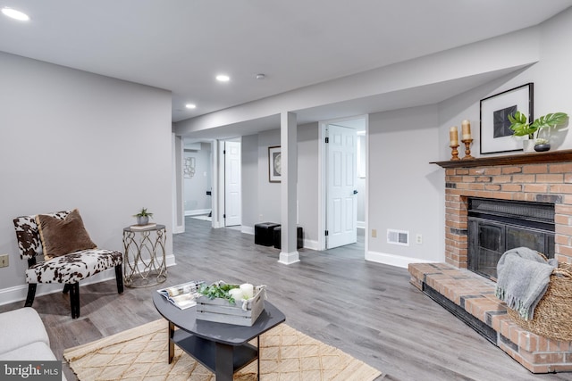 living room featuring recessed lighting, visible vents, a fireplace, and wood finished floors