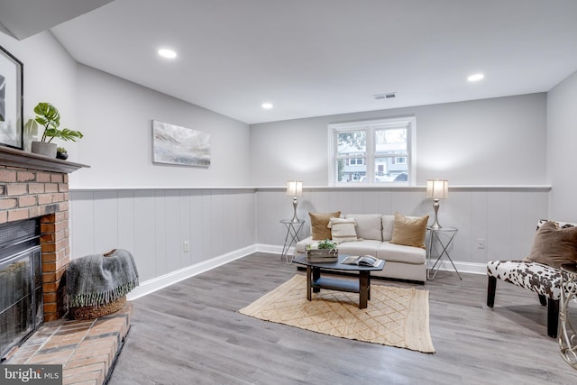 living area featuring a fireplace, recessed lighting, visible vents, wainscoting, and wood finished floors