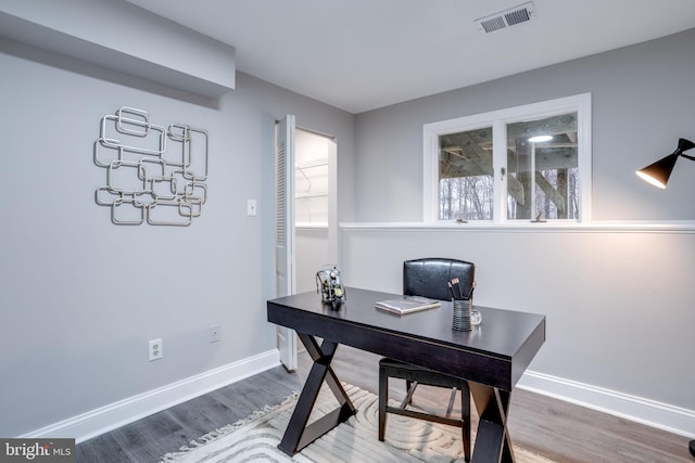 office area with wood finished floors, visible vents, and baseboards