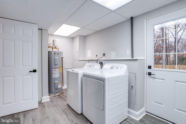 laundry room featuring laundry area, light wood-style floors, water heater, a healthy amount of sunlight, and washer and dryer