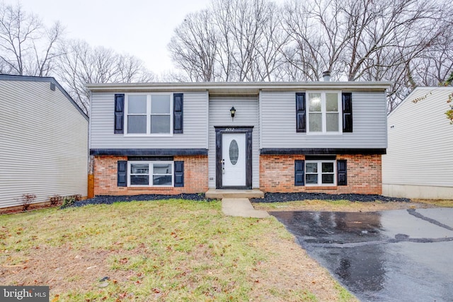 split foyer home with a front lawn and brick siding