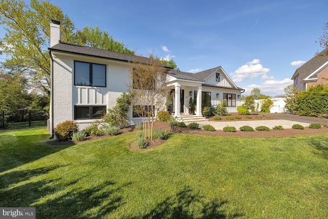 view of front of property featuring a front lawn, a chimney, and brick siding