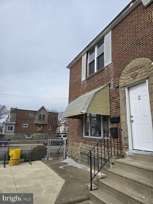 multi unit property featuring entry steps, fence, and brick siding