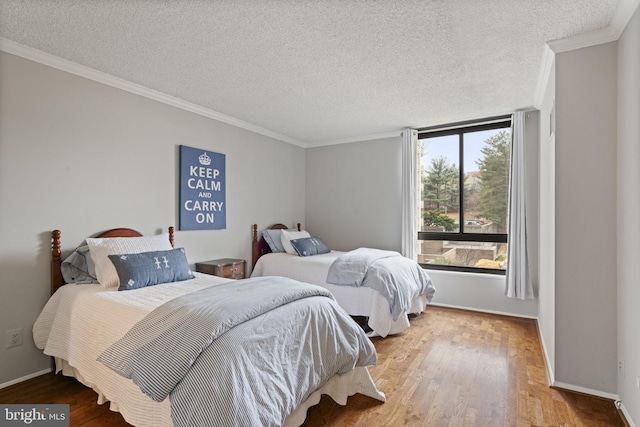 bedroom featuring crown molding, a textured ceiling, baseboards, and wood finished floors