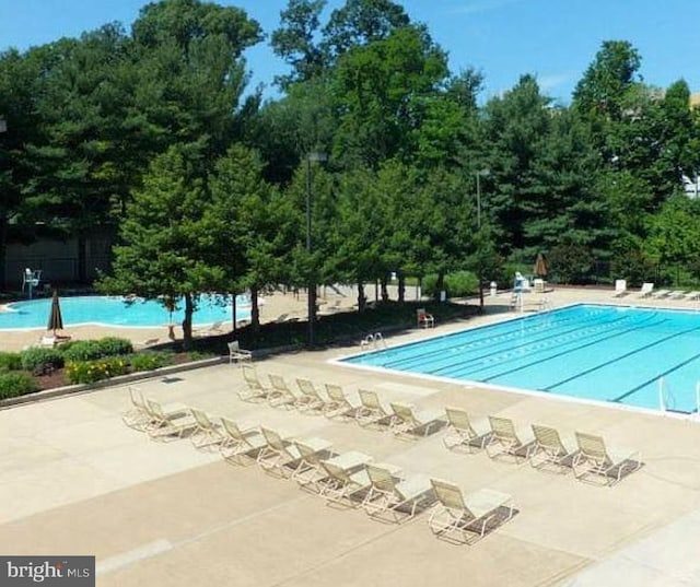 community pool with a patio and fence