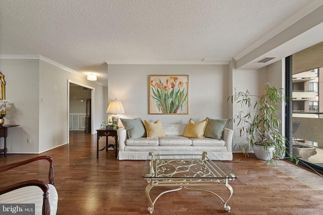 living room with a textured ceiling, dark wood finished floors, visible vents, and crown molding