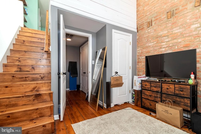 bedroom featuring baseboards, dark wood finished floors, and brick wall