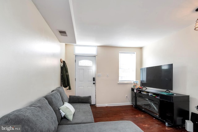 living area featuring baseboards, visible vents, and dark wood-type flooring