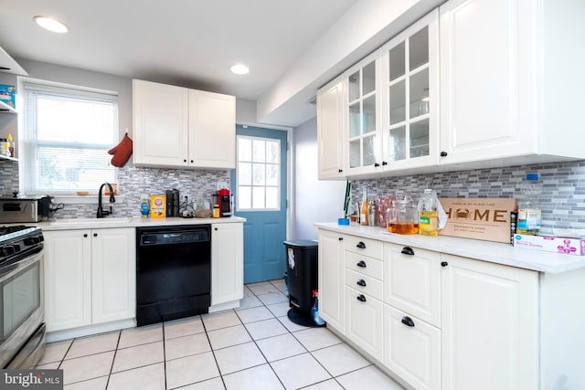 kitchen with white cabinets, black dishwasher, light countertops, stainless steel range oven, and glass insert cabinets