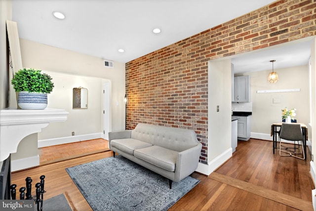 living room featuring dark wood finished floors, recessed lighting, visible vents, brick wall, and baseboards