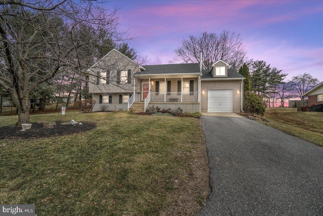 split level home with covered porch, driveway, a front yard, and an attached garage