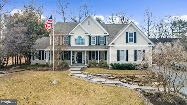 view of front of property featuring board and batten siding, a front yard, covered porch, and roof with shingles