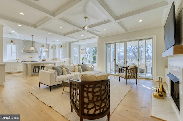 living area with light wood-style floors, a fireplace, and beamed ceiling