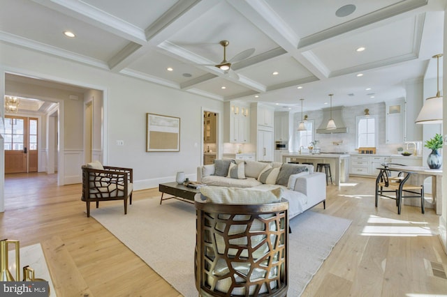 living room with beamed ceiling, coffered ceiling, and light wood-style floors