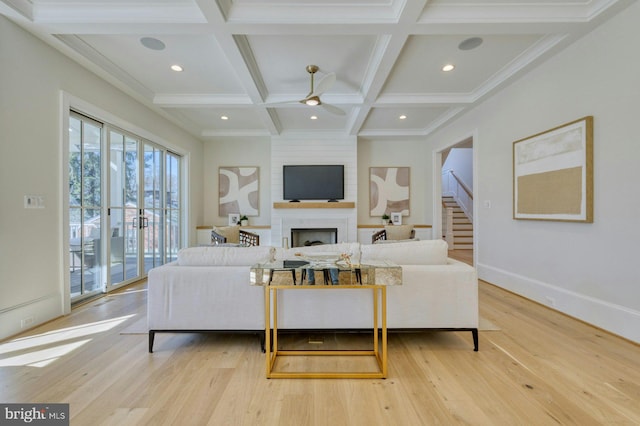 living area featuring a large fireplace, baseboards, coffered ceiling, light wood-style floors, and beam ceiling