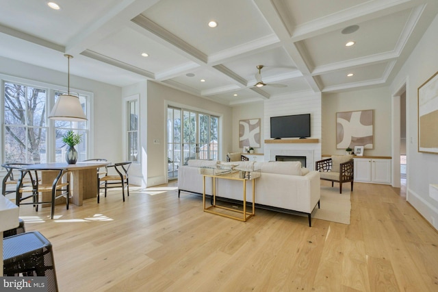 living area with light wood-type flooring, a large fireplace, coffered ceiling, and beamed ceiling