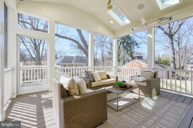 sunroom / solarium featuring ceiling fan and vaulted ceiling with skylight