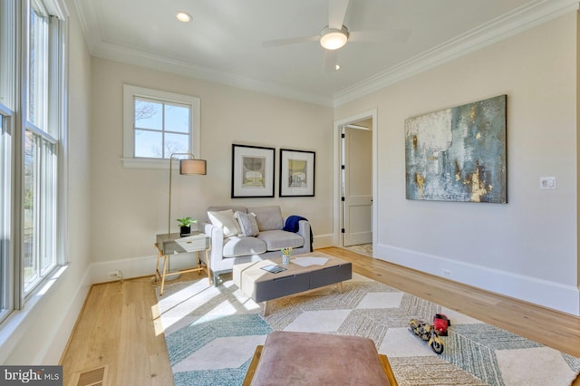 living room featuring light wood-style flooring, visible vents, baseboards, and ornamental molding