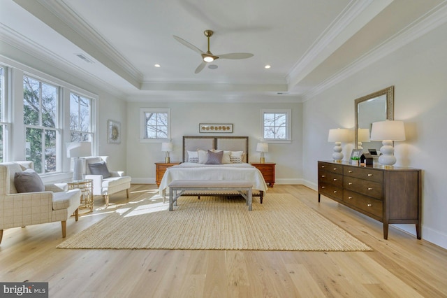 bedroom with light wood-style flooring, visible vents, and a tray ceiling